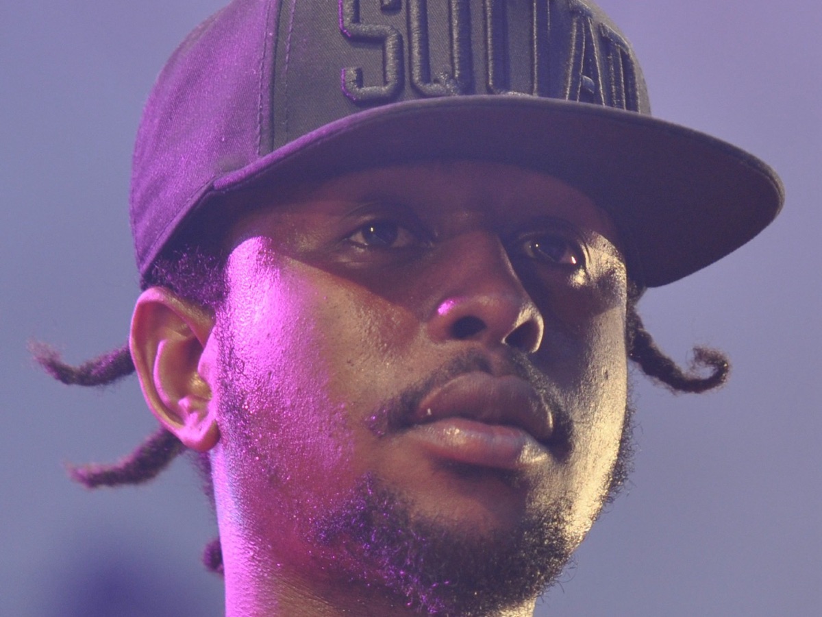 Popcaan on stage in a black cap